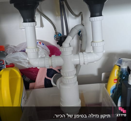 צנרת מתחת לכיור עם חיבורים וכלים לניקוי